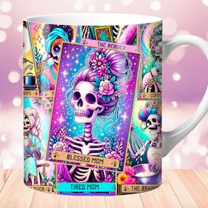 May include: White ceramic mug with a colorful design featuring a skeleton with flowers in its hair. The design includes multiple tarot card-like images with text such as "The Reader", "Blessed Mom", "Tired Mom", and "The Baking".