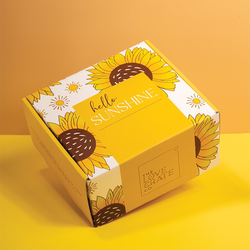 May include: A yellow box with a sunflower design and the text "hello sunshine" and "The Love Crate Co."