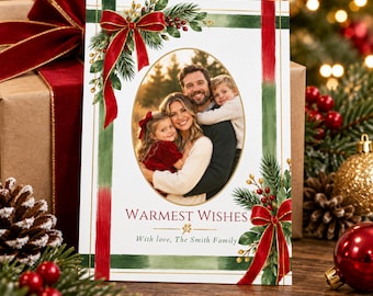 May include: A rectangular holiday greeting card featuring a central oval photo of a family. The card has a white background with green and red painted stripes, decorated with watercolor pine branches, red berries, and red bows. Text reads WARMEST WISHES.