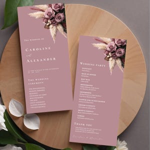 May include: Two mauve wedding programs with floral arrangements of roses and pampas grass. The programs list the wedding ceremony details and wedding party names. The text includes the names Caroline and Alexander.