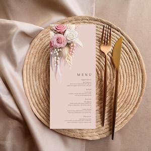 Op de afbeelding: Een zachtroze menukaart met bloemaccenten, een gouden vork en een mes, op een geweven placemat. Het menu bevat voorgerechten, salade, hoofdgerecht en dessertopties. Het menu is versierd met roze en witte rozen.