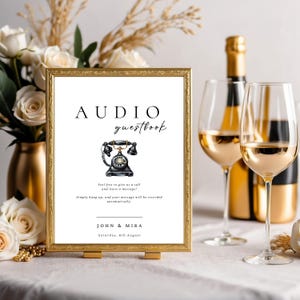 May include: A white sign with a gold frame and a black rotary phone illustration. The sign reads "AUDIO guestbook" and "Feel free to give us a call and leave a message! Simply hang up, and your message will be recorded automatically." The sign also includes the names "JOHN & MIRA" and the date "Saturday, 5th August".