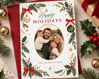 May include: A rectangular holiday greeting card featuring a central oval photo of a family. The card has a white background with green pine branches, red holly berries, gold stars, and red bows. Text reads Happy HOLIDAYS and xoxo, the Johnson Family.