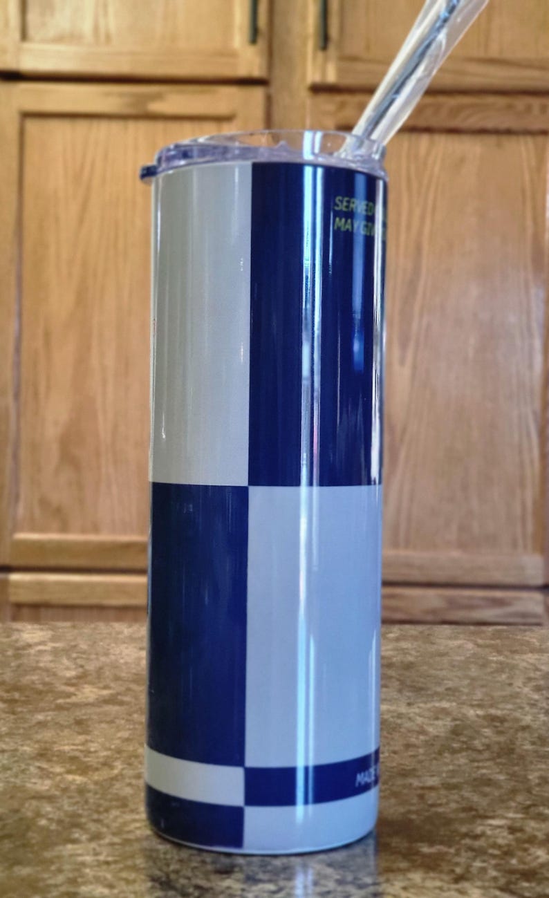 Pu&ograve; includere: Un bicchiere in acciaio inossidabile con un motivo a scacchi blu e bianco. Il bicchiere ha un coperchio trasparente e una cannuccia. Il testo "Servito il 1 maggio" e "Made in China" &egrave; visibile sul bicchiere.