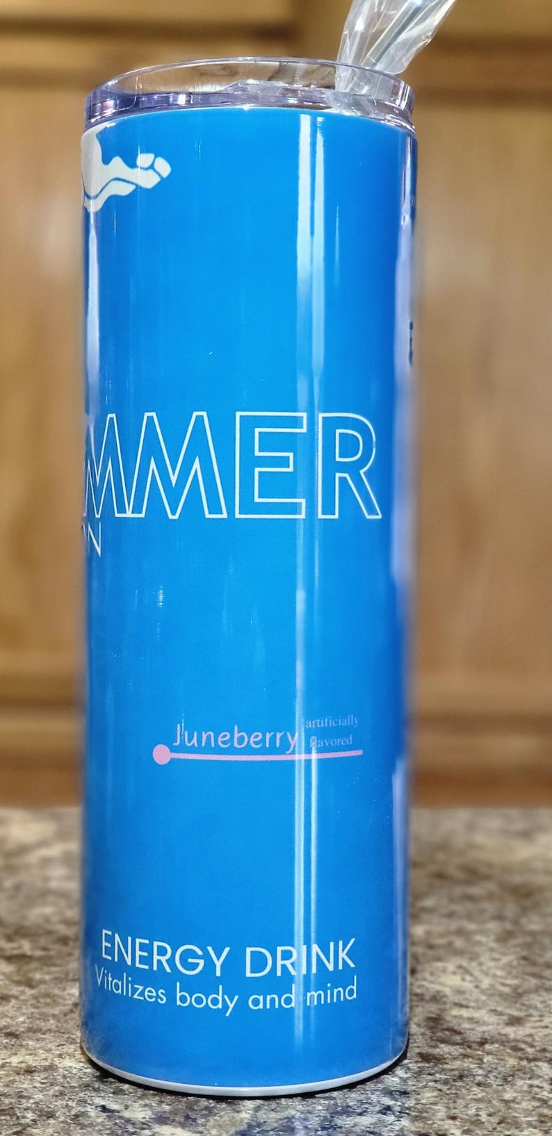 Może przedstawiać: Niebieski kubek termiczny ze stali nierdzewnej z napisem "SUMMER" w białym kolorze. Kubek ma r&oacute;żową kropkę i napis "Juneberry sztucznie aromatyzowany" w białym kolorze. Na dole kubka znajduje się napis "ENERGY DRINK Witalizuje ciało i umysł" w białym kolorze.