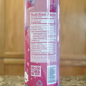 May include: A cylindrical beverage container with a pink and blue design. The container features a nutrition facts label with details on calories, vitamins, and other nutritional information. The design includes a dripping effect and fruit illustrations.