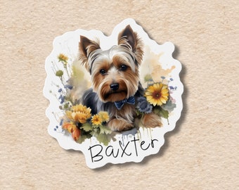 Puede incluir: Una pegatina con una ilustración a la acuarela de un Yorkshire Terrier con pajarita azul, rodeado de flores amarillas y azules. El nombre del perro, "Baxter", está escrito en cursiva debajo.
