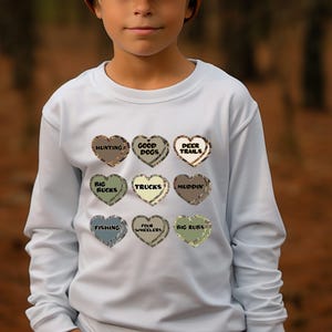 May include: Light blue long-sleeved sweatshirt with a camouflage pattern of nine hearts, each with a different phrase inside. The phrases are "Hunting", "Good Dogs", "Deer Trails", "Big Bucks", "Trucks", "Muddin'" , "Fishing", "Four Wheelers", and "Big Ruts".