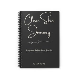 Puede incluir: Un cuaderno negro con espiral con las palabras "Clear Skin Journey" en blanco. También muestra "Progress. Reflections. Results." y el nombre de la marca "AZ SKIN REHAB".
