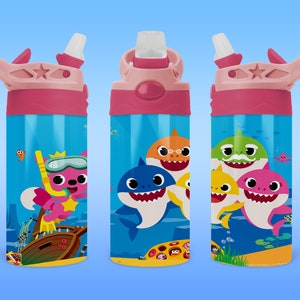 Puede incluir: Una botella de agua azul con ilustraciones de tiburones de dibujos animados y una tapa y pajita rosas. El diseño incluye un zorro rosa con un esnórquel y un barco hundido. La botella está diseñada para niños.