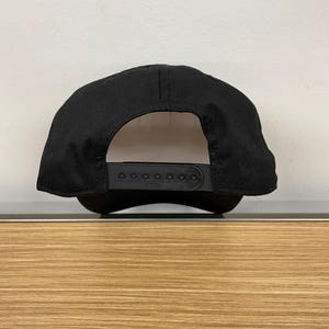 May include: Black baseball cap with a black adjustable strap and a white label that says "ZYNIA".
