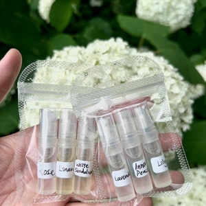 May include: Five small clear glass bottles with white labels. The labels have the following text: Rose, Linen, White Sandalwood, Lavender, and Inner Peace. The bottles are in a clear plastic bag.