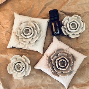 May include: Four white ceramic flower-shaped diffusers with a small brown glass bottle of essential oil.
