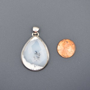 May include: A silver pendant with a white and gray agate stone. The stone is faceted and has a dendritic pattern. The pendant is about the size of a US penny.