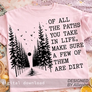May include: A light pink t-shirt with a black graphic of a forest path and the text "OF ALL THE PATHS YOU TAKE IN LIFE, MAKE SURE A FEW OF THEM ARE DIRT." The words "digital download" and "DESIGNED BY Allephe" are also printed on the shirt.