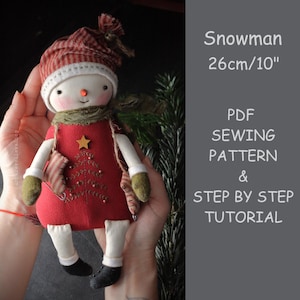 May include: A handmade snowman doll, approximately 10 inches tall, with a red dress, striped hat, and green scarf. The doll has a carrot nose, a stitched mouth, and a star on the front. The image also includes text that says "Snowman" and "PDF Sewing Pattern & Step by Step Tutorial."