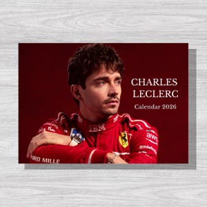 Könnte beinhalten: Ein Kalender mit Charles Leclerc in einem roten Rennanzug. Der Kalender hat den weißen Text "CHARLES LECLERC Calendar 2026". Der Hintergrund ist tiefrot.