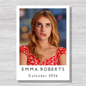 Könnte beinhalten: Ein Kalender mit einem Porträt von Emma Roberts. Sie trägt ein rotes Oberteil mit Blumenmuster und blickt nach oben mit einem nachdenklichen Ausdruck. Der Kalender trägt die Aufschrift "EMMA ROBERTS Calendar 2026".