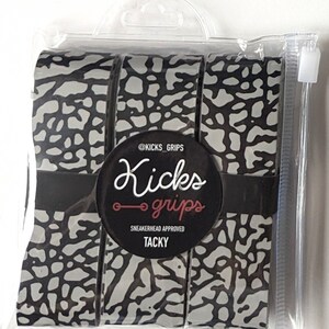May include: A set of three rolls of adhesive grip tape featuring a grey and black elephant print pattern. The rolls are secured by a black paper band with the text @KICKS_GRIPS, Kicks grips, SNEAKERHEAD APPROVED, and TACKY, all inside a clear plastic bag.