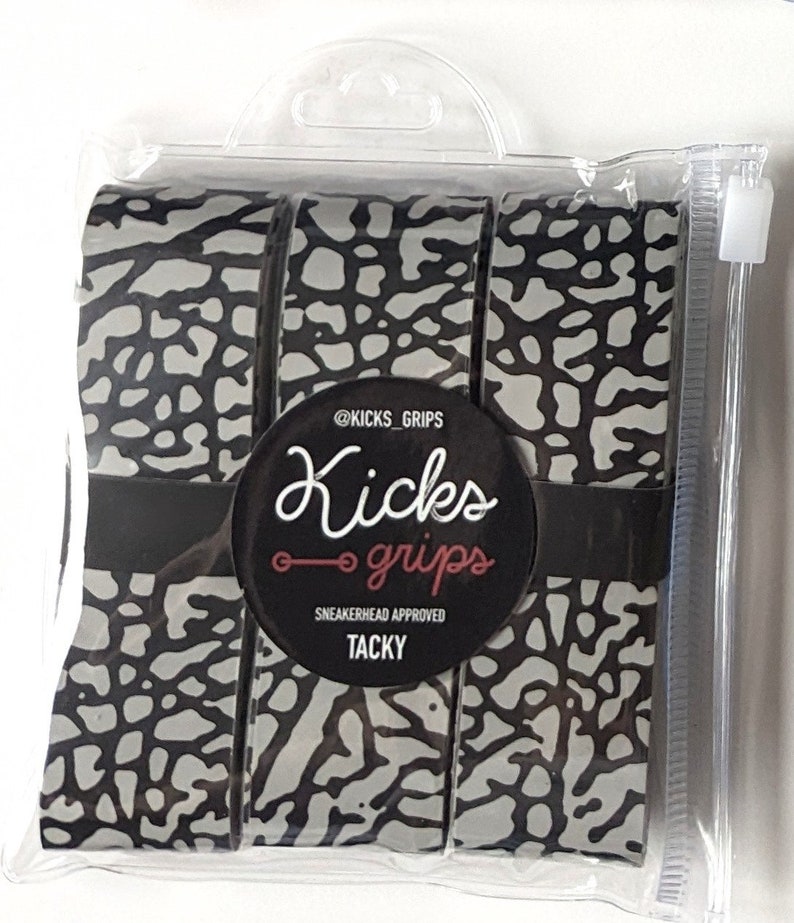 May include: A set of three rolls of adhesive grip tape featuring a grey and black elephant print pattern. The rolls are secured by a black paper band with the text @KICKS_GRIPS, Kicks grips, SNEAKERHEAD APPROVED, and TACKY, all inside a clear plastic bag.