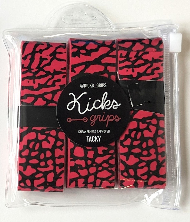 May include: Three rolls of red and black elephant print grip tape packaged in a clear plastic pouch. A circular black label features the text @KICKS_GRIPS, Kicks grips, SNEAKERHEAD APPROVED, and TACKY. The tape is secured with a black paper band.