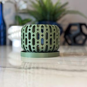May include: A green planter with a geometric pattern and a matching saucer. The planter is made of a lightweight material and has a modern design.
