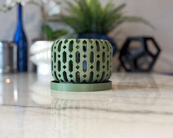 May include: A green planter with a geometric pattern and a matching saucer. The planter is made of a lightweight material and has a modern design.