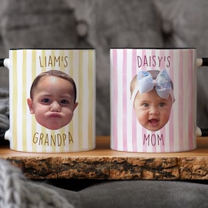 K&ouml;nnte beinhalten: Zwei Keramikbecher mit schwarzen Griffen und R&auml;ndern. Ein Becher hat ein gelb-wei&szlig; gestreiftes Muster mit einem Kindergesicht und dem Text "LIAM'S GRANDPA". Der andere Becher hat ein rosa-wei&szlig; gestreiftes Muster mit einem Kindergesicht und dem Text "DAISY'S MOM".