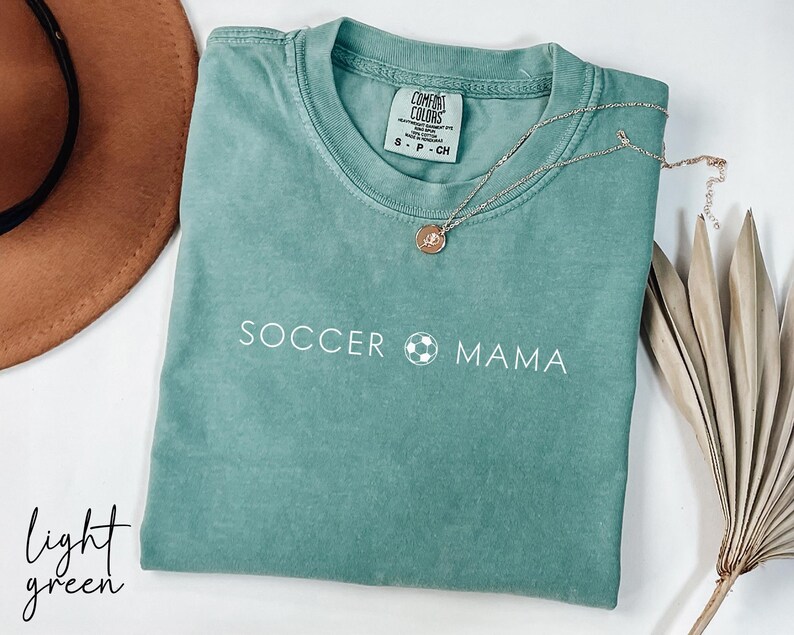 May include: Light green t-shirt with the text "Soccer Mama" and a soccer ball graphic.