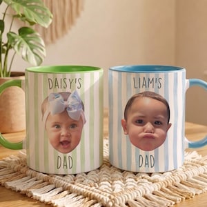 K&ouml;nnte beinhalten: Zwei Keramikbecher mit personalisierten Babyfotos. Ein Becher hat einen gr&uuml;nen Griff und Rand, vertikale gr&uuml;n-wei&szlig;e Streifen und den Text "DAISY'S DAD". Der andere Becher hat einen blauen Griff und Rand, vertikale blau-wei&szlig;e Streifen und den Text "LIAM'S DAD".