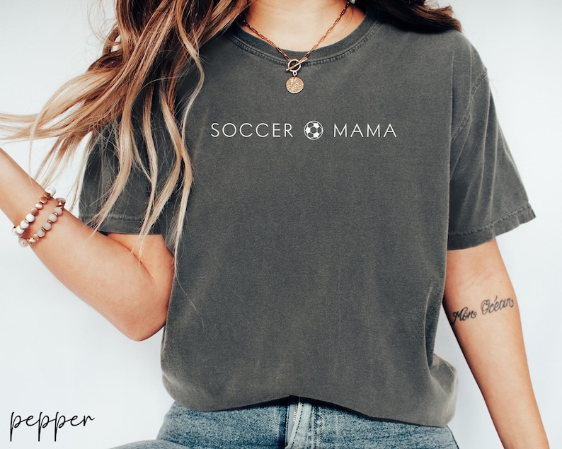 May include: A gray t-shirt with the text "SOCCER MAMA" and a soccer ball graphic printed on the front.