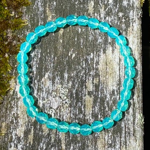 Puede incluir: Un brazalete de piedras preciosas azul turquesa con cuentas facetadas. El brazalete está hecho de piedras naturales y está encordado en elástico.