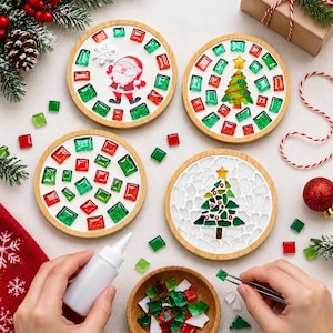 Può includere: Quattro sottobicchieri circolari in legno con disegni a mosaico a tema natalizio. Due sottobicchieri mostrano Babbo Natale e un albero con tessere di vetro quadrate rosse e verdi, uno ha tessere sparse e uno un albero fatto di frammenti di vetro.