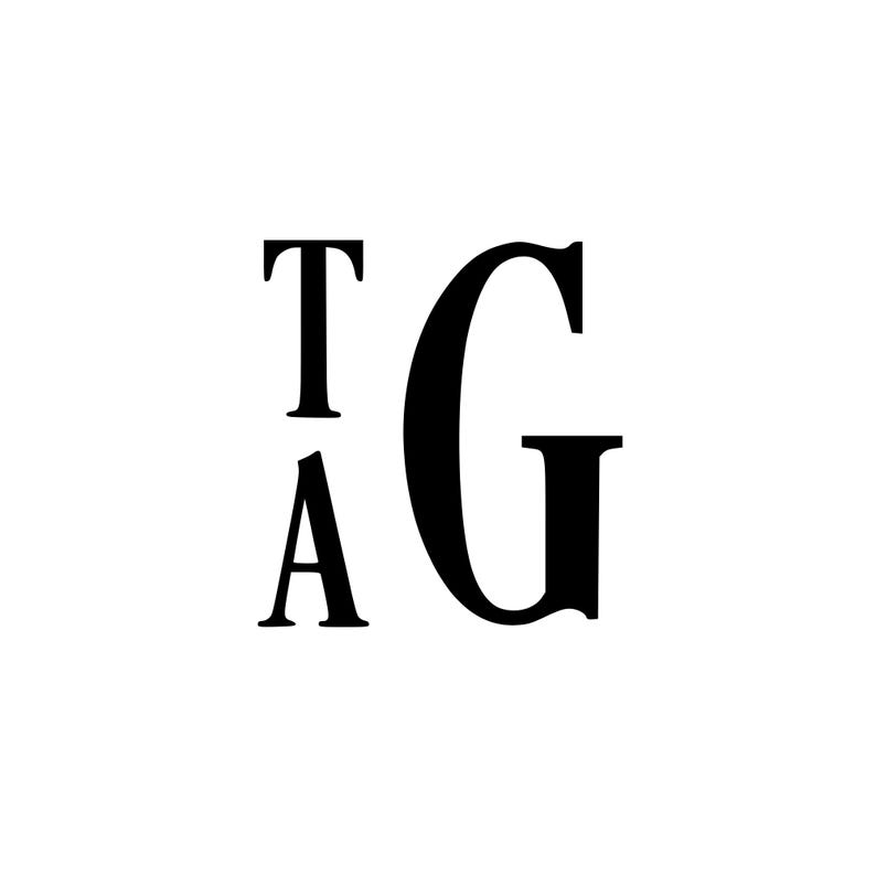 May include: Black letters spelling out the initials "TAG" on a white background. The letter "T" is above the letter "A", and the letter "G" is to the right of the "T" and "A". The letters are in a serif font.