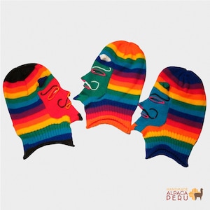May include: Three colorful knitted balaclavas with face designs. Each balaclava features a rainbow striped pattern with a different face design in red, green, and blue. The balaclavas are handmade in Peru.