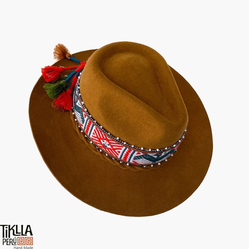 May include: A brown felt fedora hat with a colourful woven band and tassels. The band features geometric patterns in red, white, and blue, with silver beads.
