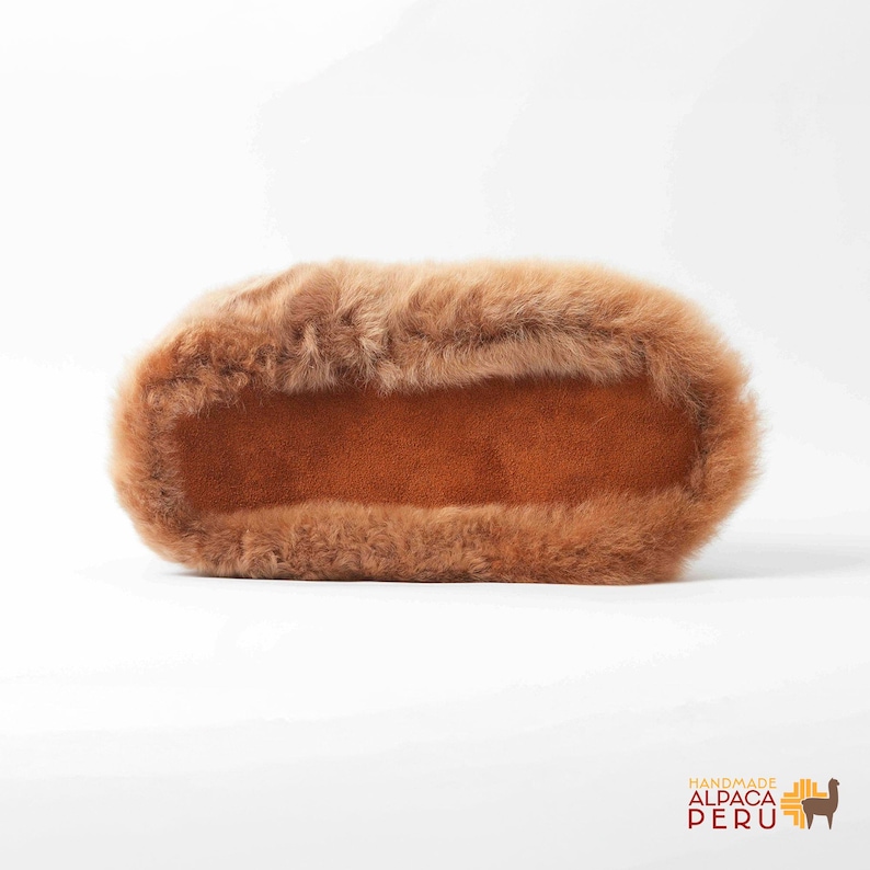 May include: A rectangular, brown alpaca fur item with a soft, plush texture. The item has a suede-like interior and a fluffy, fur exterior. The product is handmade in Peru.
