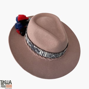 May include: A brown felt fedora hat with a braided band and a colourful tassel. The band has a geometric pattern in black and white.