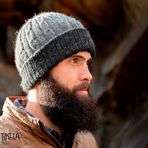 Puede incluir: Un gorro de punto gris y negro con un borde doblado. El gorro está hecho de lana de alpaca y está hecho a mano en Perú. El texto "TIKLLA PERU" es visible en la esquina inferior izquierda de la imagen.