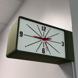 May include: A rectangular wall clock with a white face, black numerals, and black lines radiating from the center. The clock hands are red, and the frame is olive green. The clock is mounted on a white wall.