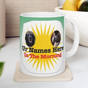 Peut inclure: Mug en céramique blanche avec un fond vert et un motif représentant un chien et un chat. Le motif comprend le texte "Ur Names Here In The Morning" en noir et rouge, avec une étoile jaune.