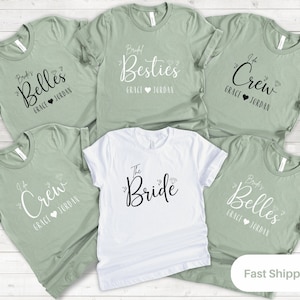 May include: Set of six green and white t-shirts with text that reads "Bride's Belles", "Bride's Besties", "The Bride", "I'm the Crew", and "I'm the Crew".