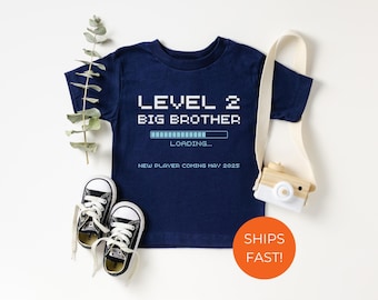 May include: A navy blue t-shirt with the text "LEVEL 2 BIG BROTHER" and a progress bar that says "LOADING..."  The text "NEW PLAYER COMING MAY 2023" is below the progress bar.