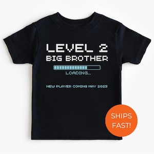 May include: Black t-shirt with a blue and white graphic that says "Level 2 Big Brother. Loading... New Player Coming May 2023"