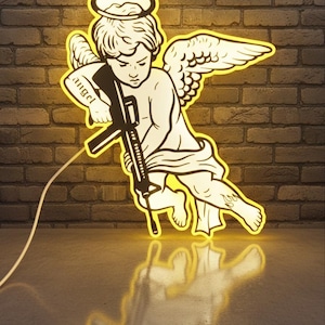 May include: A neon sign depicting a cherubic angel figure holding a rifle. The sign is outlined in a bright yellow color, with the word "angel" written on the angel's arm. The background is a brick wall.
