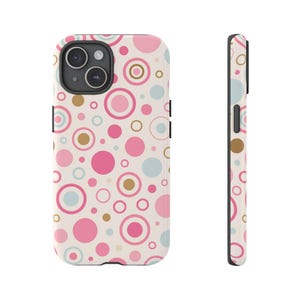 May include: A phone case featuring a repeating pattern of pink, light blue, and gold circles on a cream background. The case is shown from the front and side, showcasing the design and camera aperture.