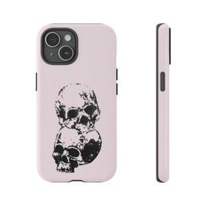 May include: A pink phone case with a black and white illustration of two skulls stacked on top of each other.
