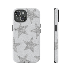 Pode incluir: Uma capa de telefone branca com um padrão de estrelas de glitter prata. A capa tem um para-choque preto e um recorte para a câmera.