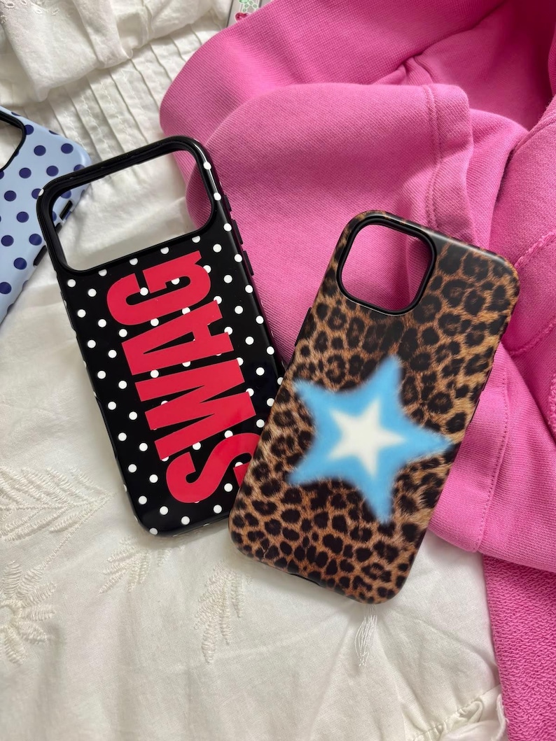 May include: Two smartphone cases. One case is black with white polka dots and the word SWAG in large red letters. The other case features a brown and black leopard print pattern with a central light blue star graphic with a white center.