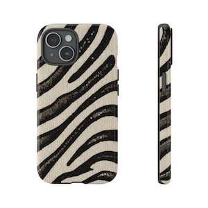 以下が含まれることがあります： ゼブラストライプ模様の携帯電話ケース。ケースは黒と白で、テクスチャ加工された表面とカメラの切り抜きがあります。側面図はケースの厚さとデザインを示しています。
